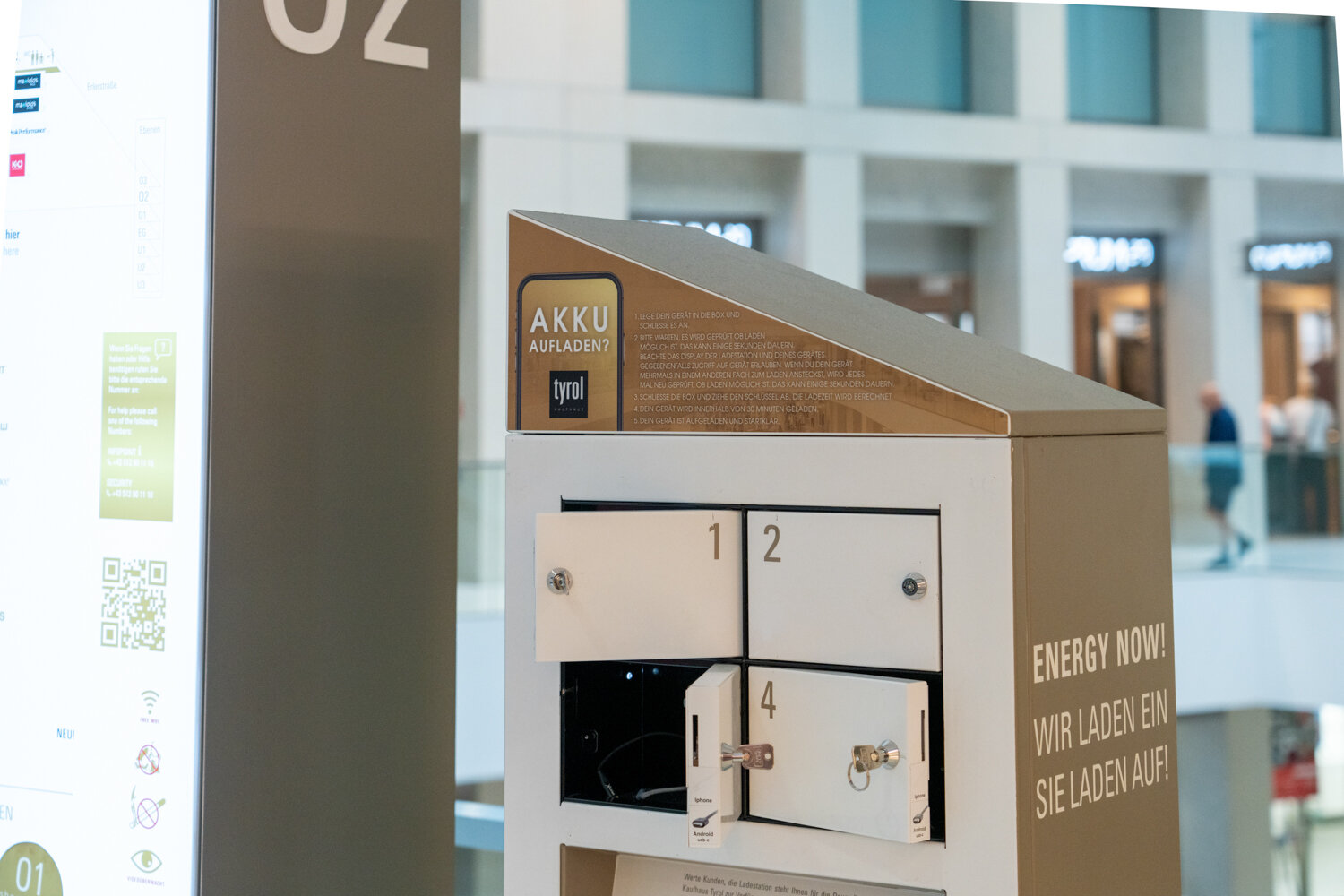 Weiße Akku-Ladestation mit abschließbaren Schließfächern und Ladekabeln für Smartphones im Kaufhaus Tyrol.
