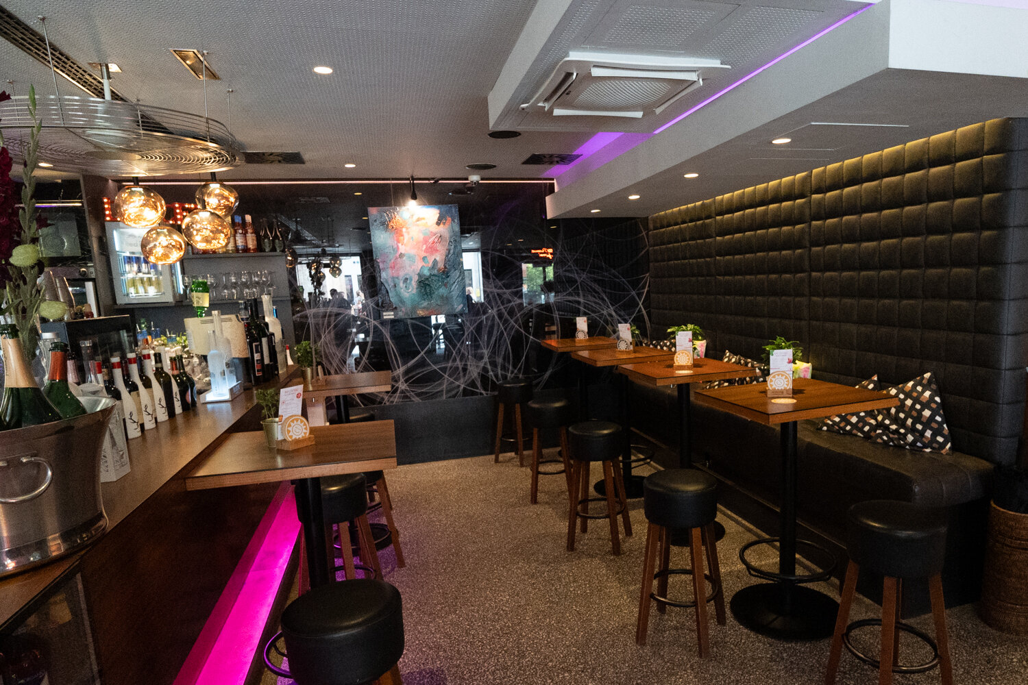 Gemütlicher Sitzbereich mit Holzstehtischen, Barhockern und Designer-Kugel-Leuchten in der Bar Centrale.