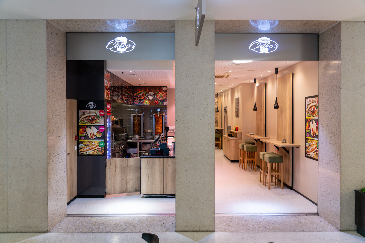 Frontansicht des Imbissrestaurants Cütko’s im Einkaufszentrum mit Verkaufsbereich, Döner-Spießen und modernem Sitzbereich.