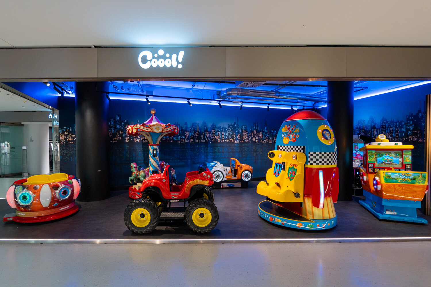 Bunter Kinder-Spielbereich Cooool! mit Karussell, Rakete, Mini-Monster-Truck und Fahr-Automaten.