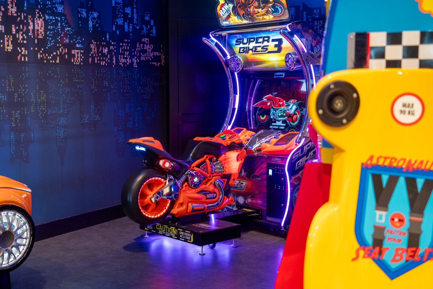 Leuchtend orangefarbener Motorrad-Rennspiel-Simulator Super Bikes 3 im Cooool-Spielbereich.