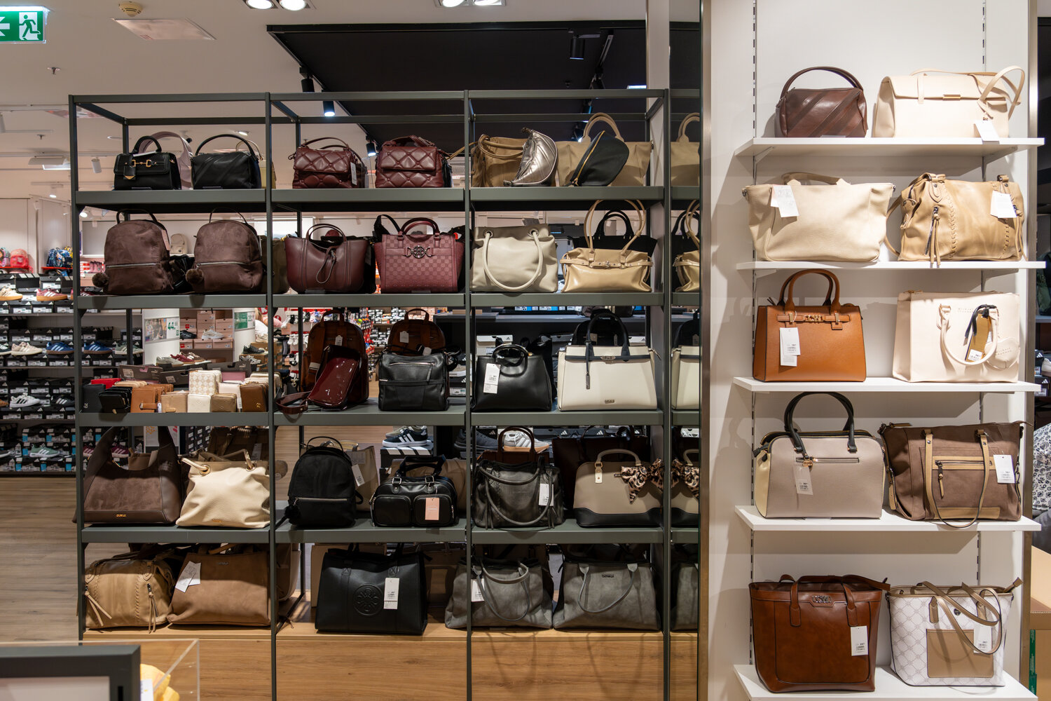 Großes Sortiment an Damenhandtaschen, Rucksäcken und Umhängetaschen in Metall- und Holzregalen bei Deichmann.