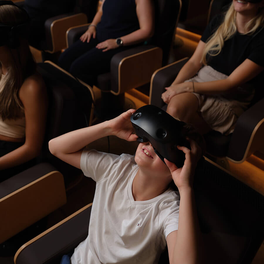 Besucher in Sesseln erleben eine virtuelle Welt mit modernen VR-Brillen.