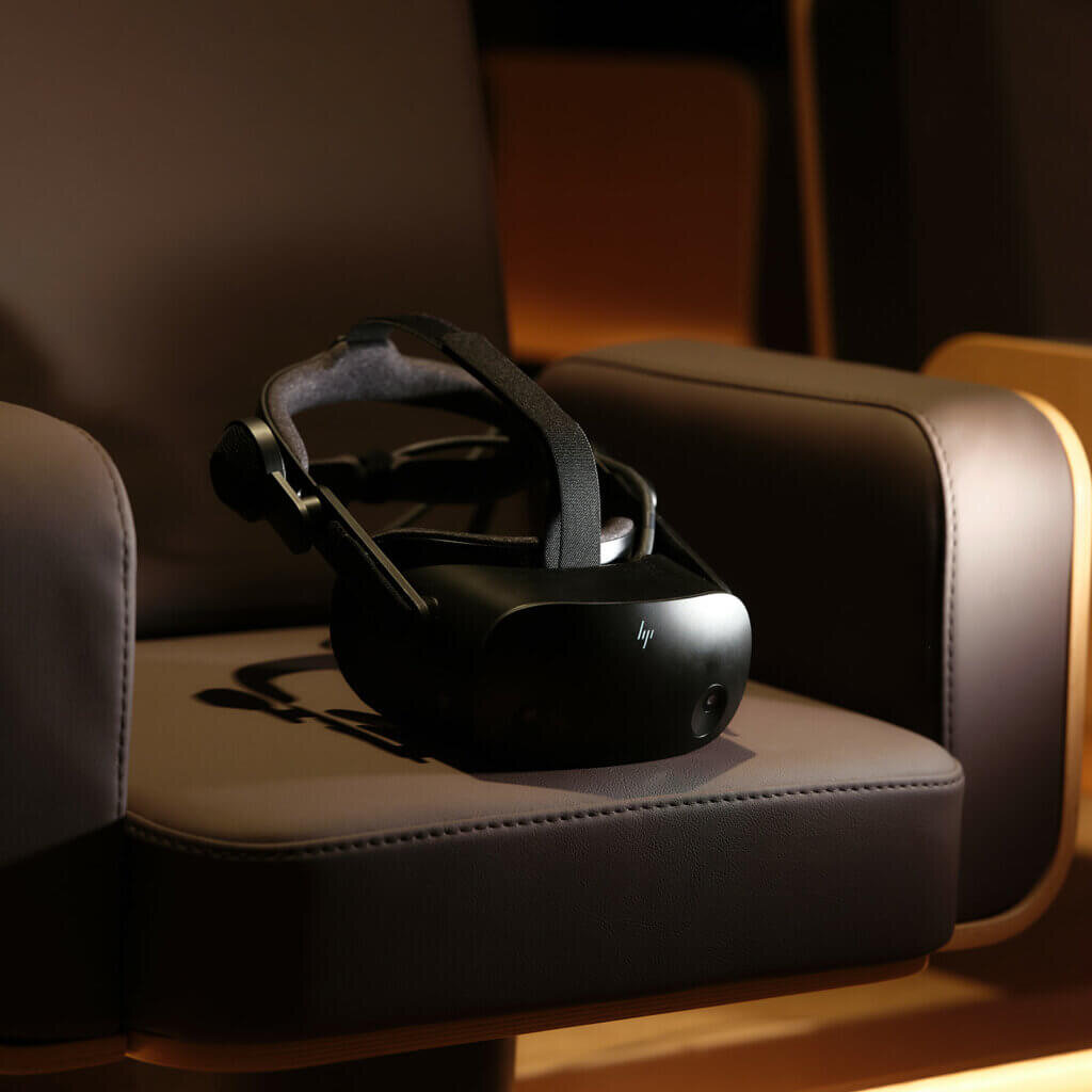Eine schwarze Virtual-Reality-Brille liegt bereit für den Einsatz auf einem gepolsterten Kinosessel.