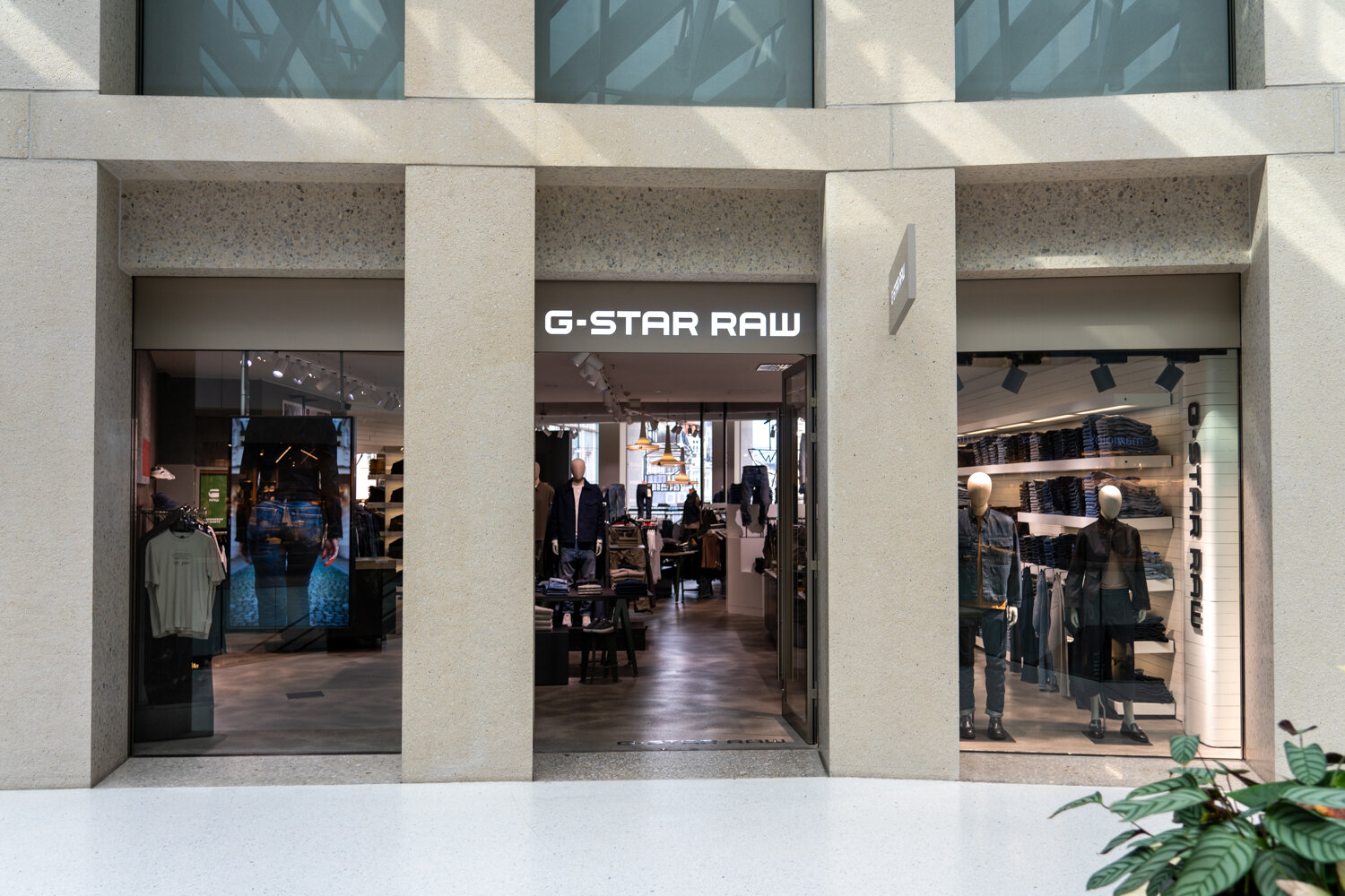 Fassade und Eingang eines G-Star RAW Modegeschäfts im Einkaufszentrum mit Schaufensterpuppen und Jeans-Ausstellung.