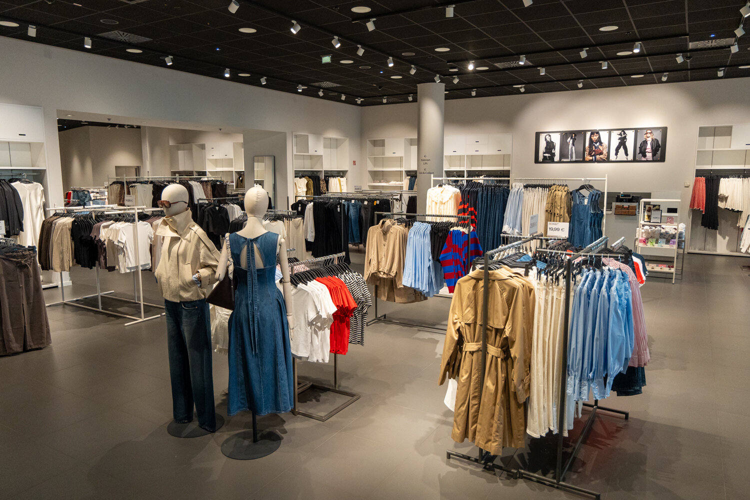 Geräumige H&M-Damenabteilung mit Kleiderständern, Trenchcoats, Jeans und Schaufensterpuppen auf der Verkaufsfläche.