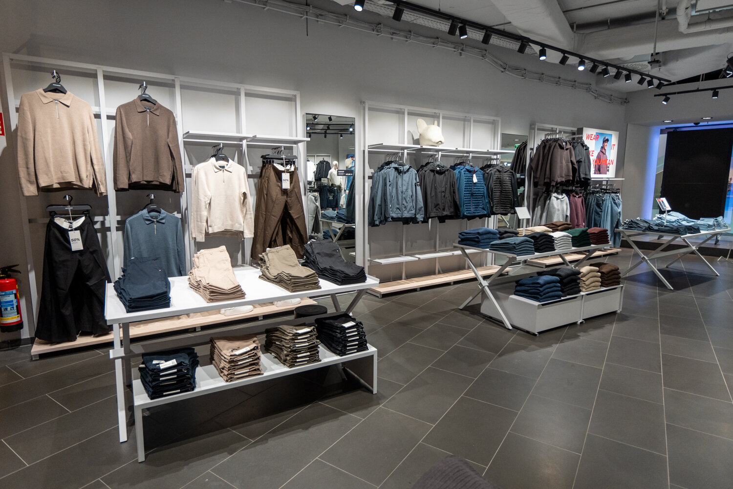 Verkaufsraum von Jack & Jones mit Pullovern, Jacken und Hosen-Ständern.