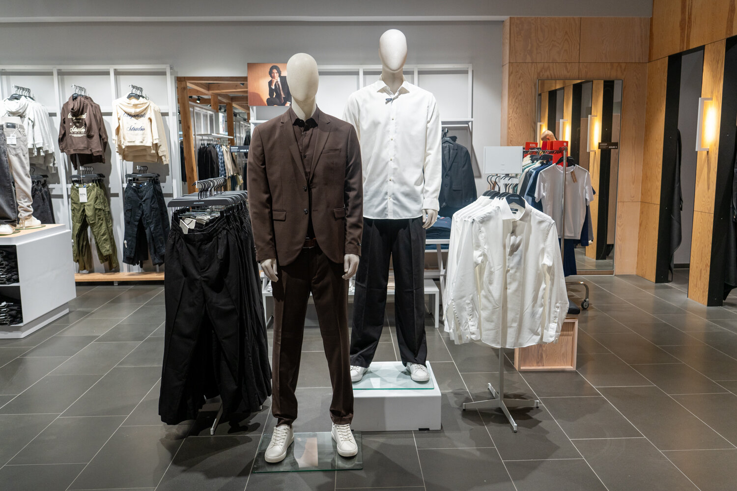 Zwei Schaufensterpuppen im Jack & Jones Modegeschäft in eleganter Herrenbekleidung mit Anzug, Hemd und passenden Stoffhosen.