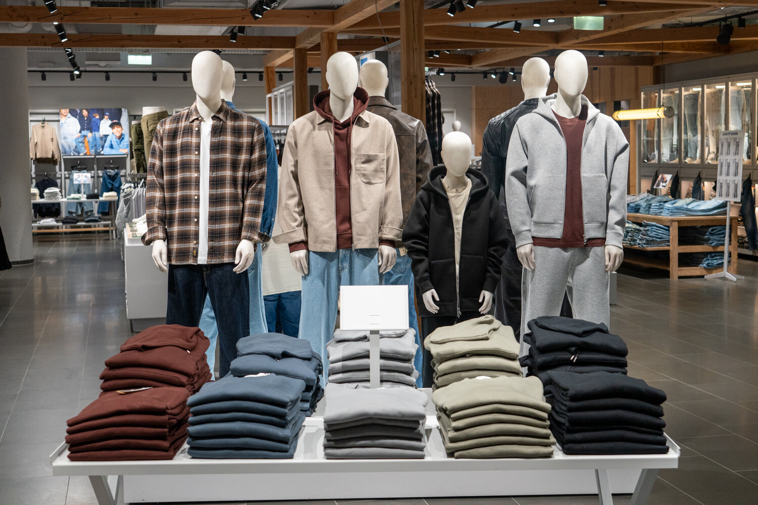 Frontale Ansicht von mehreren Schaufensterpuppen bei Jack & Jones, die lässige Casual-Wear und gefaltete Pullover präsentieren.