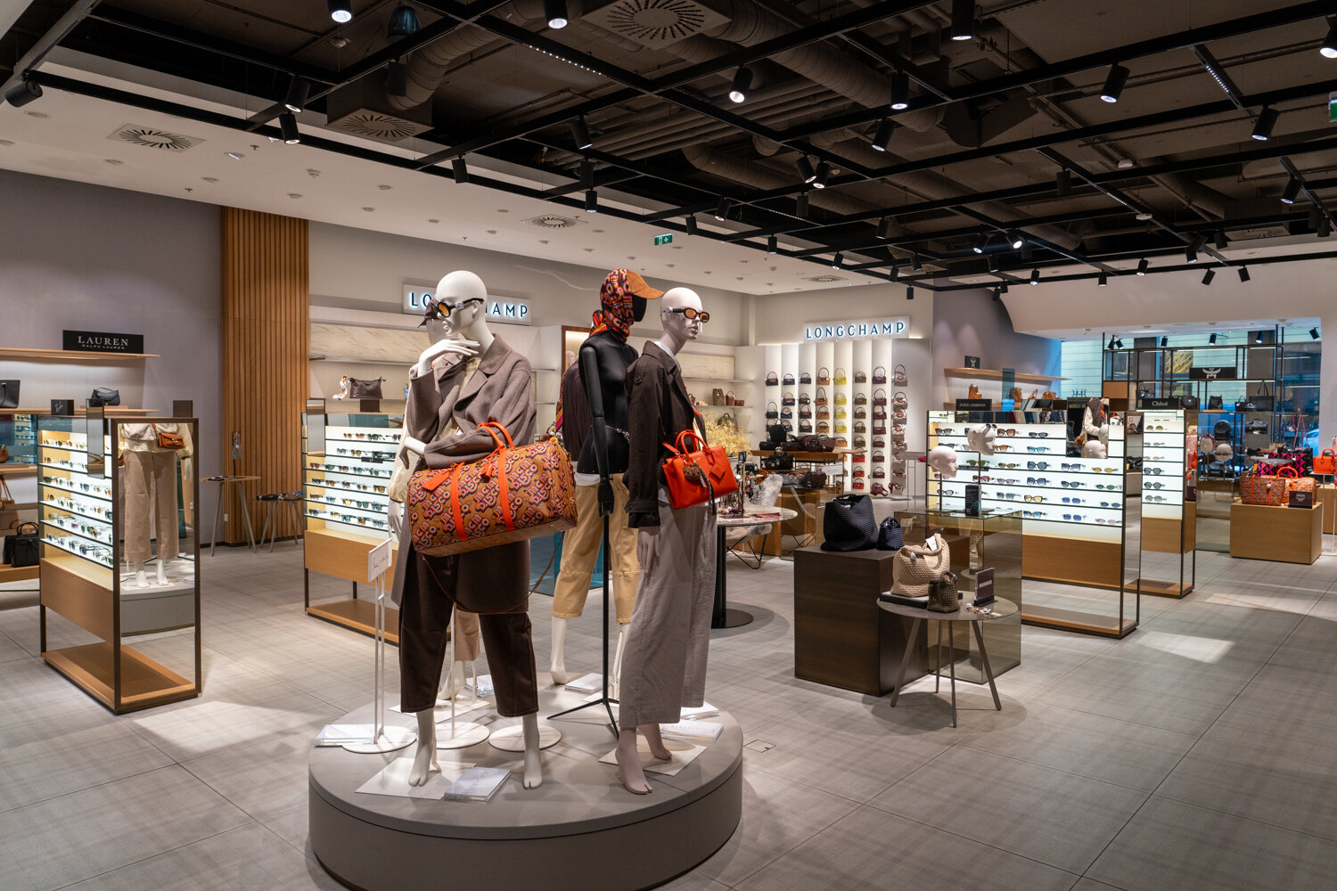 Verkaufsfläche bei Kastner & Öhler mit Schaufensterpuppen, Handtaschen von Longchamp, Brillenregalen und Marken-Accessoires.