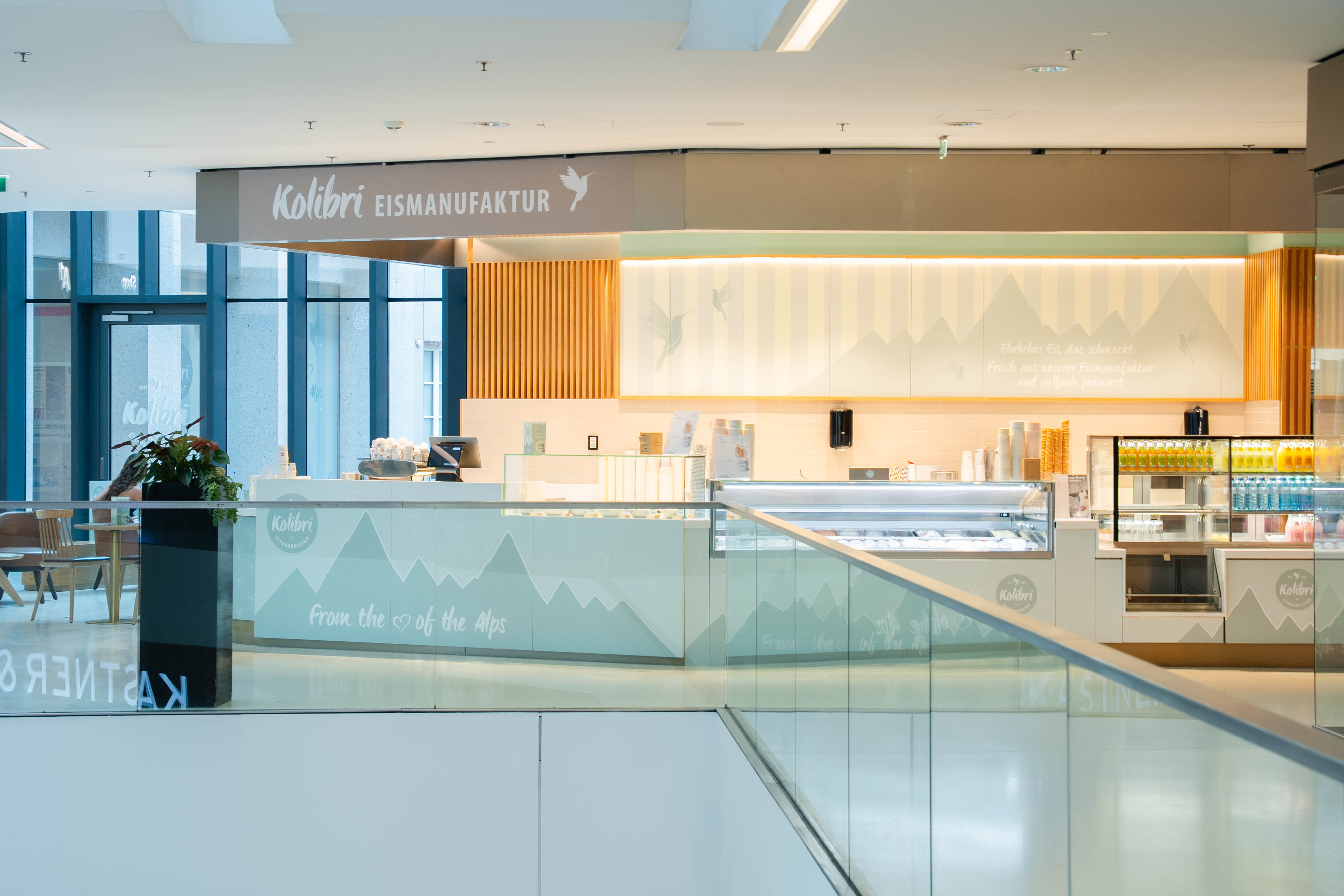 Moderner Verkaufsstand der Kolibri Eismanufaktur im Kaufhaus Tyrol mit Eisvitrine und Getränkekühlung.