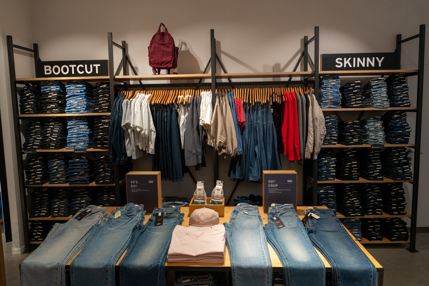 Verkaufsbereich bei Levi’s mit präsentierten Denim-Jeans auf Tischen und geordneten Regalen für Bootcut und Skinny Modelle.
