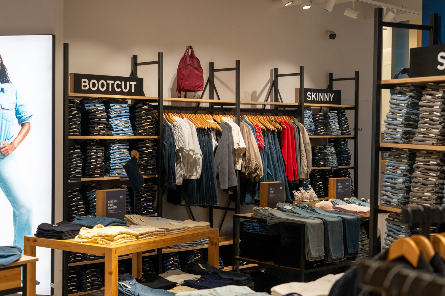 Regalwand im Levi’s Store mit sortierten Stapeln an Bootcut- und Skinny-Jeans sowie hängender Bekleidung.