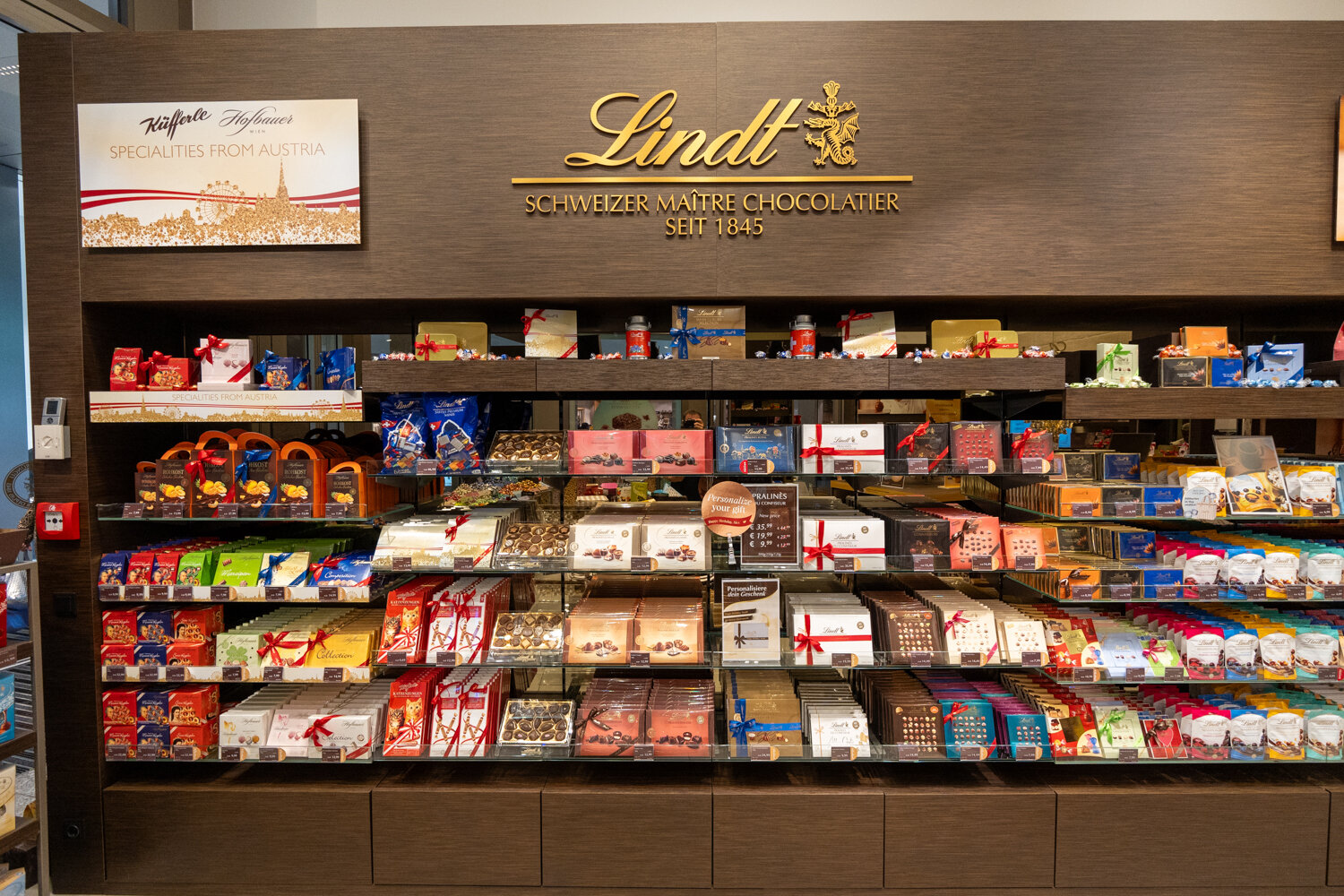Lindt Schokoladen-Regalwand mit großer Auswahl an Pralinenschachteln.