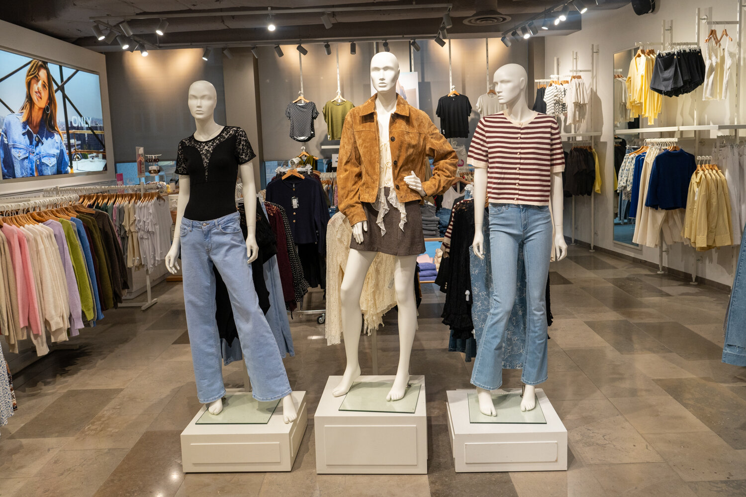 Drei Schaufensterpuppen in einem ONLY Bekleidungsgeschäft präsentiert mit aktuellen Modetrends wie Jeans, Jacken und Oberteilen.