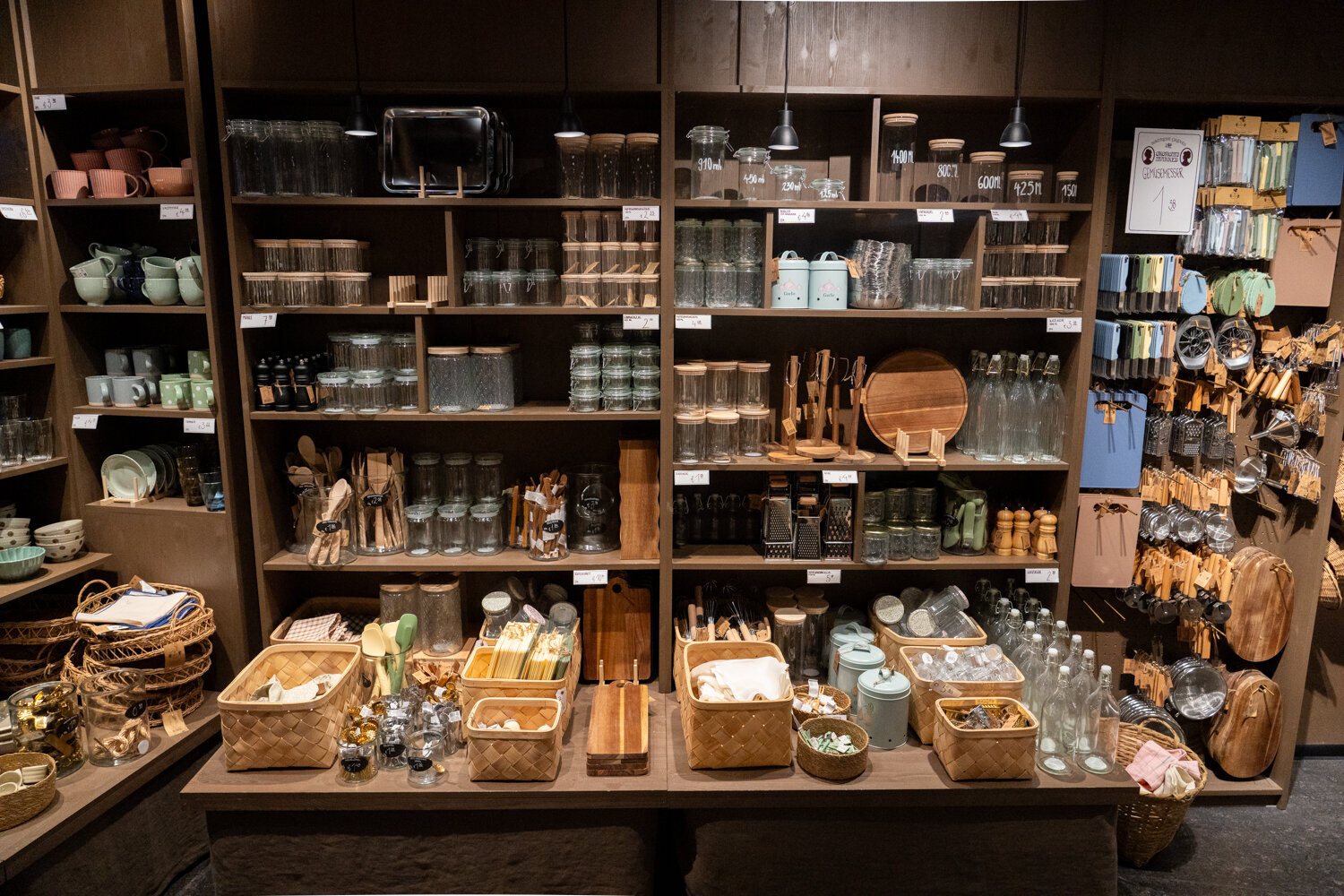 Küchendeko- und Utensilienregal bei Søstrene Grene mit Vorratsgläsern, Geschirr, Holzbrettchen und Küchenhelfern.