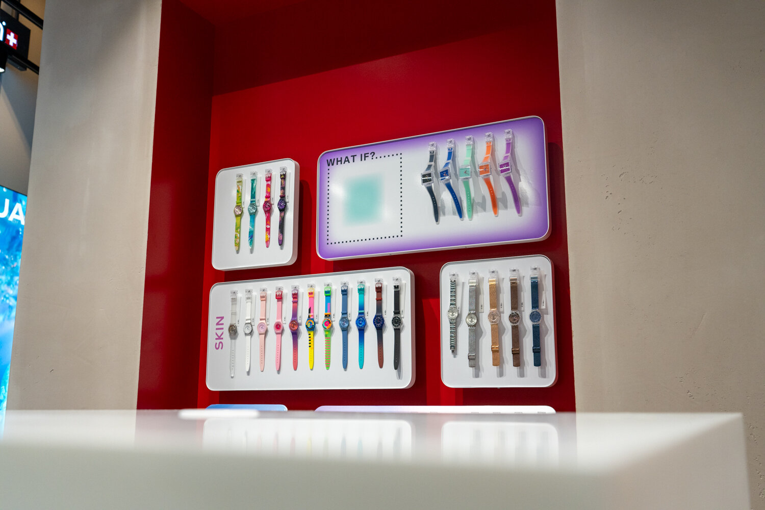 Rote Wandnische im Swatch Store mit Displays verschiedener Kollektionen wie What If und Skin.