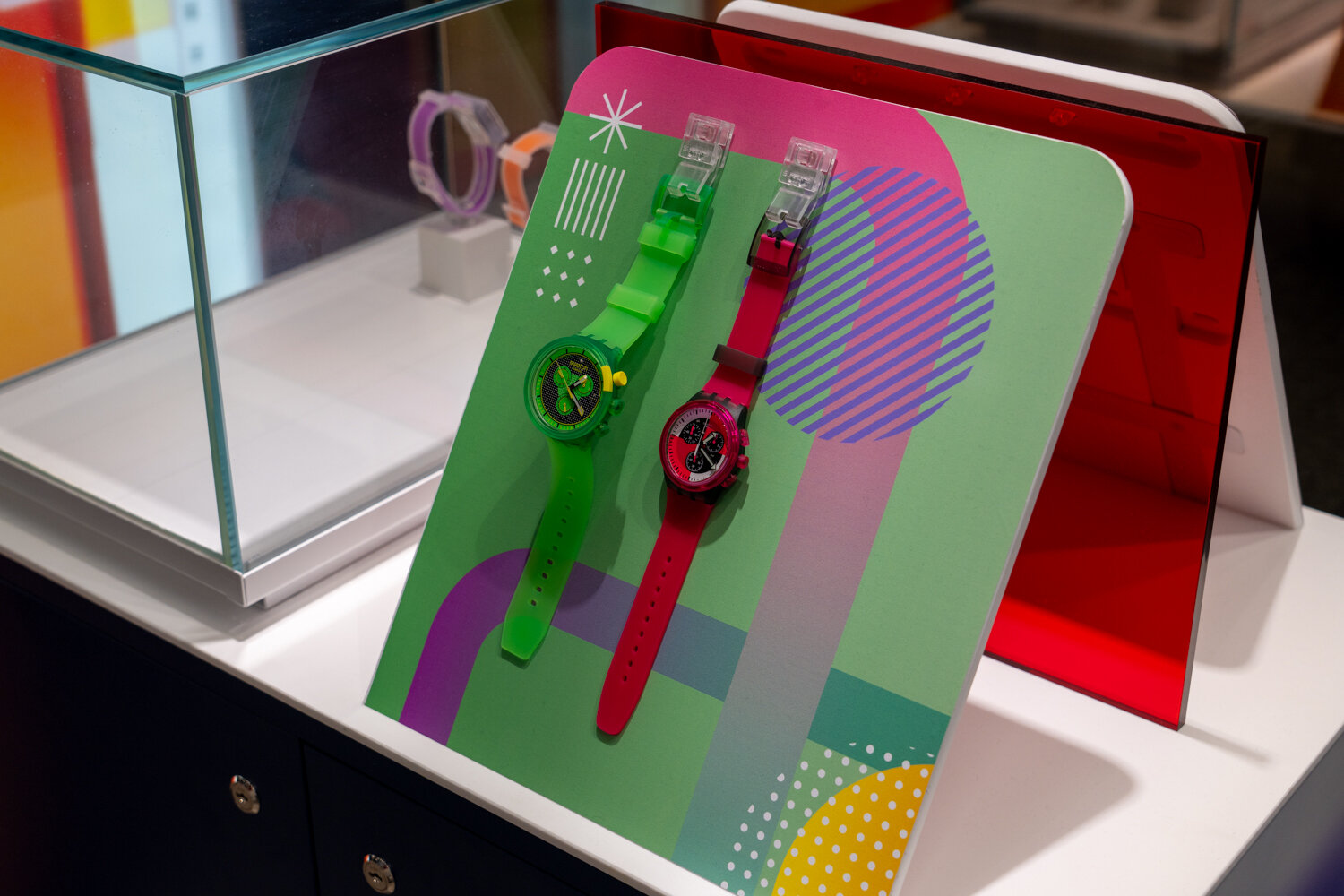 Display-Aufsteller bei Swatch mit zwei Armbanduhren in grün und rot.