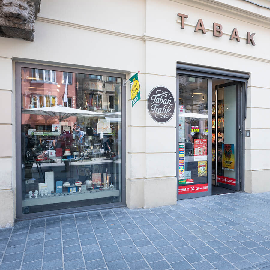 Außenansicht der Trafik Blaas im Kaufhaus Tyrol mit einem dekorativen Schaufenster voller Pfeifen und Zubehör neben der Eingangstür.