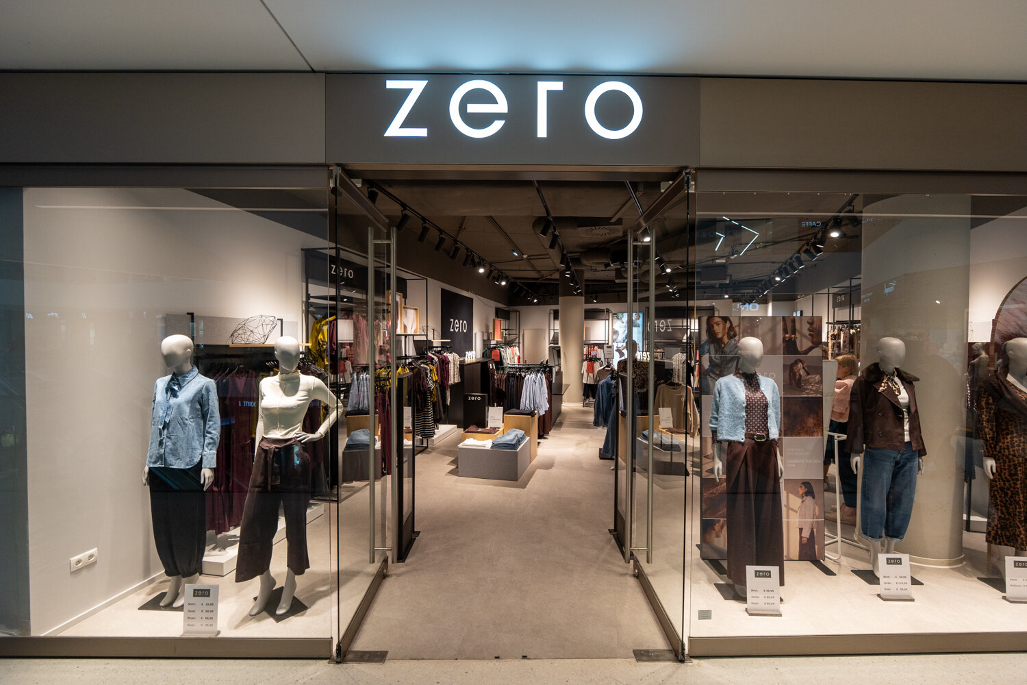 Frontansicht der zero-Filiale im Einkaufszentrum mit beleuchtetem Markenlogo, Schaufensterpuppen und Blick auf Damenmode.