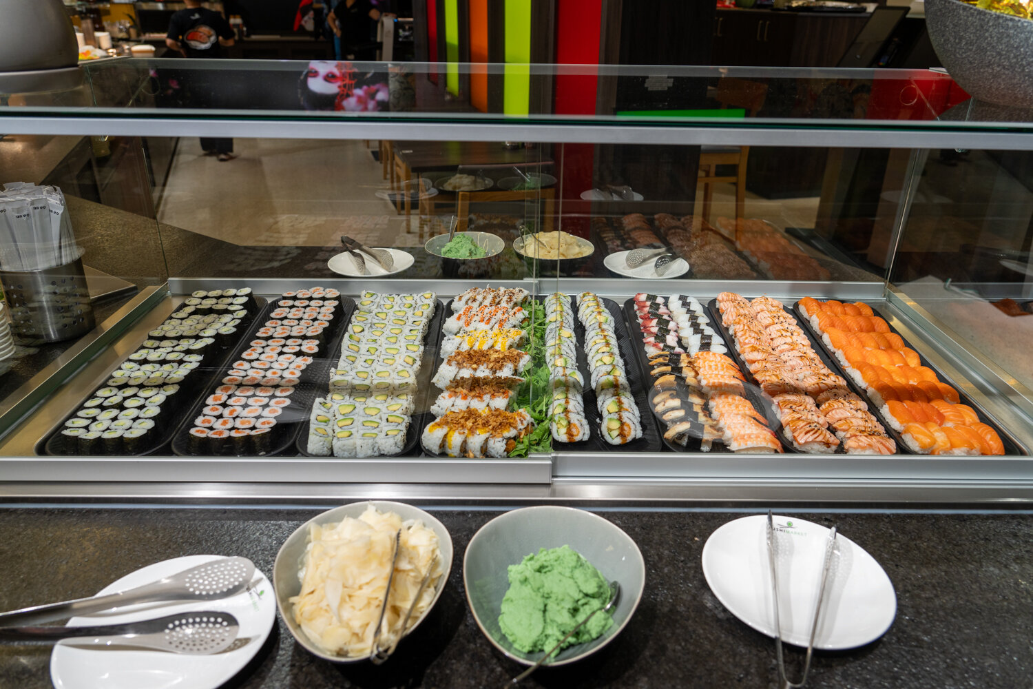 Gläserne Sushi-Vitrine bei Zushi Market gefüllt mit Maki, Inside-Out-Rolls, Nigiri, Wasabi und Ingwer.
