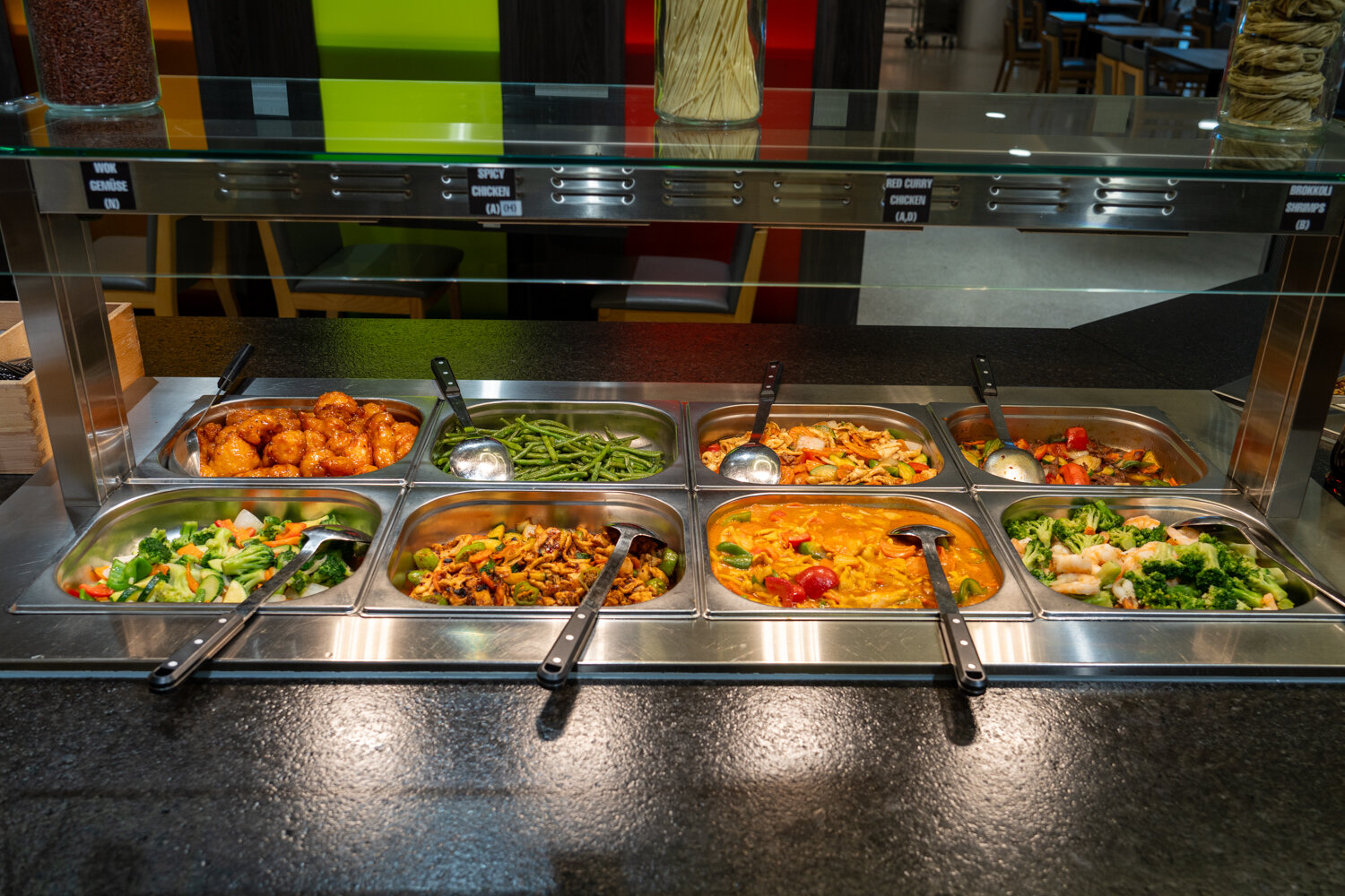 Edelstahlschalen im Zushi Market Buffet mit Wok-Gemüse, Hähnchen in Soße, Curry und Brokkoli mit Garnelen.